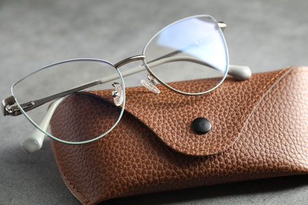 Case with stylish glasses on grey table, closeup