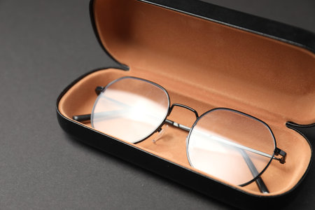 Case with stylish glasses on gray background, closeup
