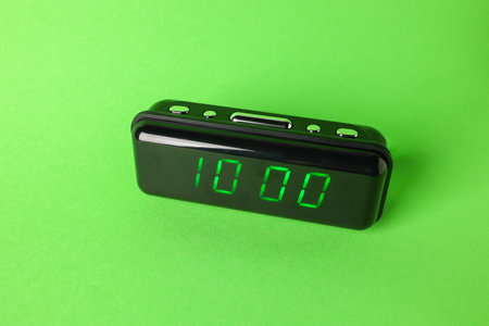 Digital alarm clock showing 10:00 o'clock on green background
