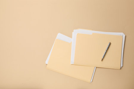 File folders with papers and pen on beige background, flat lay. Space for textの写真素材