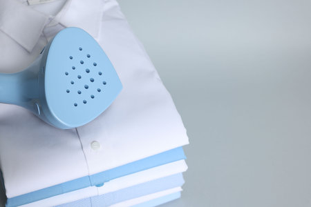 Upright steamer and stack of folded shirts on grey background, above view. Space for textの写真素材