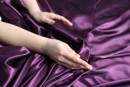 Woman on purple silk bed linens, closeupの写真素材