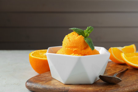 Balls of tasty orange sorbet, fresh fruit, mint and spoon on light table, closeupの写真素材