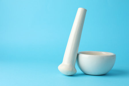 Ceramic mortar and pestle on light blue background, closeup. Space for textの写真素材