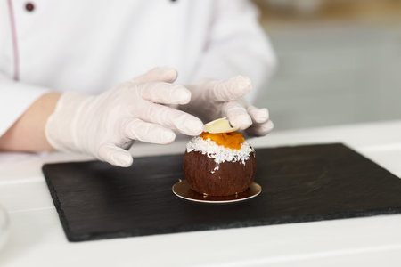 Confectioner decorating tasty dessert at white wooden table in kitchen, closeupの写真素材