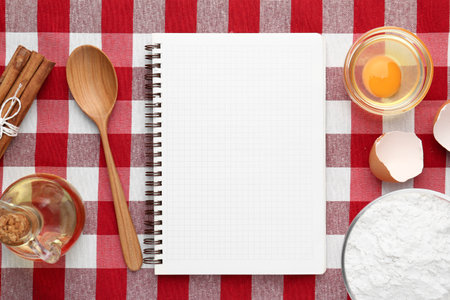 Blank recipe book, spoon and products on checkered tablecloth, flat layの写真素材