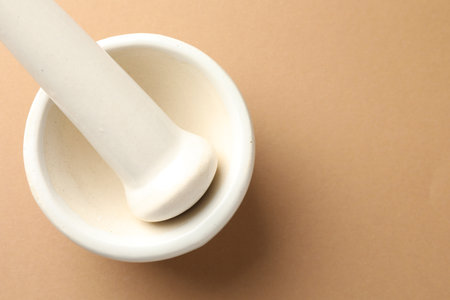 Ceramic mortar and pestle on light brown background, top view. Space for textの写真素材