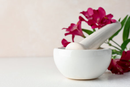 Ceramic mortar, pestle and flowers on white table, closeup. Space for textの写真素材