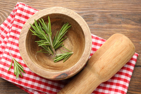 Mortar with rosemary, pestle and cloth on wooden table, flat layの写真素材