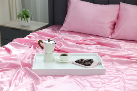 Silk linens, tray with coffee and cookies on bed at homeの写真素材