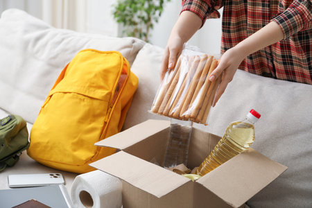 Survival kit. Woman packing different emergency supplies on sofa indoors, closeupの写真素材