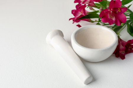 Ceramic mortar, pestle and flowers on white table, closeup. Space for textの写真素材