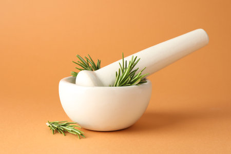 Ceramic mortar with rosemary and pestle on light brown background, closeupの写真素材