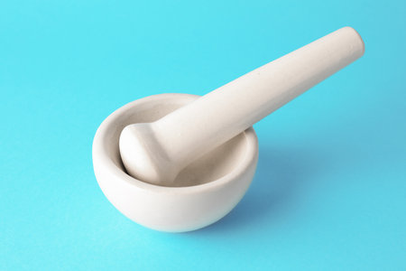 Ceramic mortar and pestle on light blue background, closeupの写真素材