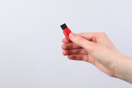 Man with modern flash drive on light grey background, closeup. Space for text