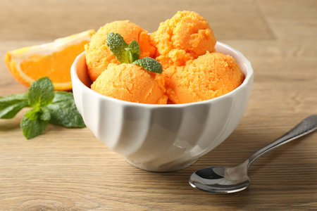 Tasty orange sorbet, fresh fruit slice and mint on wooden table, closeupの写真素材
