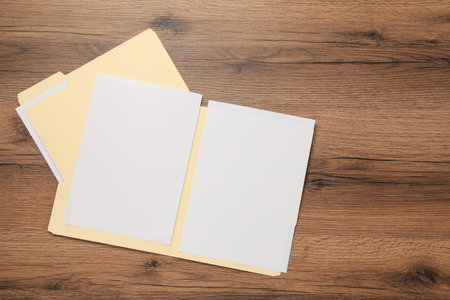 Paper file folders with blank sheets on wooden table, flat lay. Space for textの写真素材