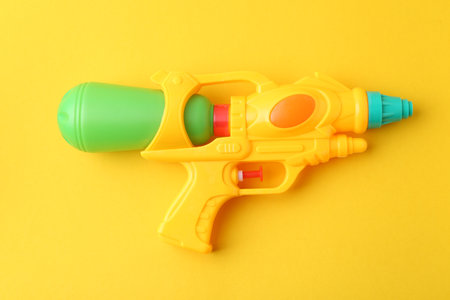 Bright plastic water gun on yellow background, top viewの写真素材