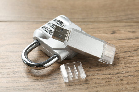 Flash drive and combination padlock on wooden background, closeup