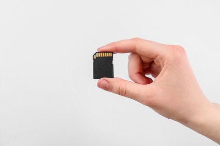 Man with SD memory card on light grey background, closeup. Space for textの写真素材