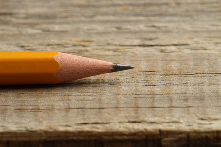 One sharp graphite pencil on wooden table, closeup. Space for textの写真素材