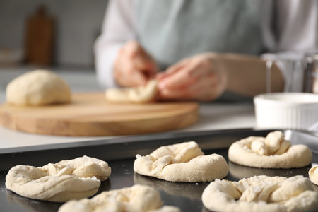 Woman shaping pretzels at table in kitchen, selective focusの写真素材