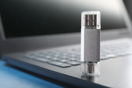 Usb flash drive and laptop on blue table, closeup