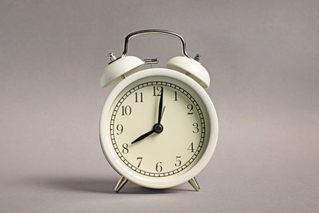 One white alarm clock on grey background