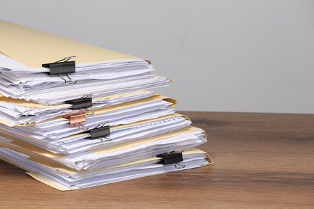 File folders with papers and binder clips on wooden table against gray background, closeup. Space for textの写真素材