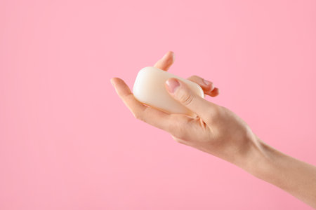 Woman with soap bar on light pink background, closeup. Space for textの写真素材
