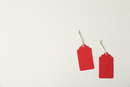 Blank tags with strings on white background, flat lay. Space for textの写真素材