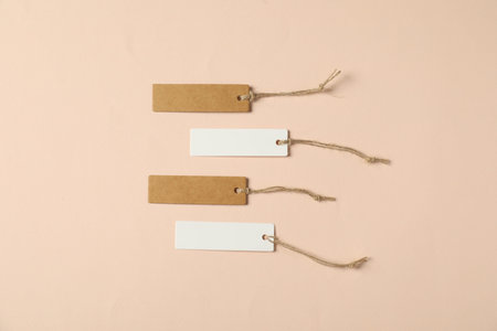 Blank tags with strings on beige background, flat layの写真素材