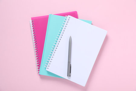 Pen and notebooks on pink background, top viewの写真素材