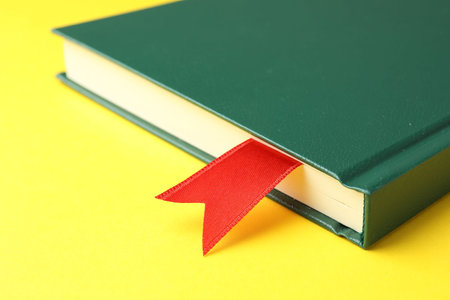 Book with red ribbon bookmark on yellow background, closeupの写真素材