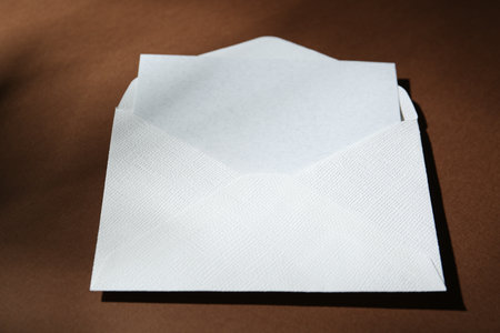Blank greeting card in paper envelope on brown background, closeupの写真素材