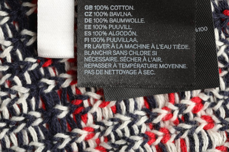 Clothing label on knitted garment as background, above view