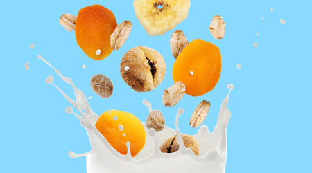 Milk splash with oat flakes and dried fruits in air on light blue background. Banner designの写真素材