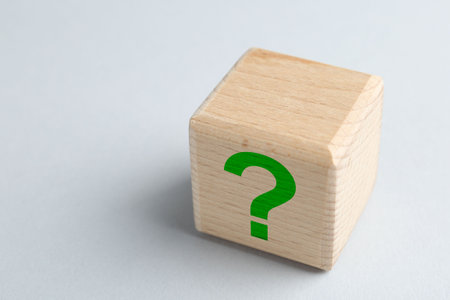 Wooden cube with green question mark on light grey background, closeupの写真素材