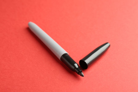 One black marker on red background, closeupの写真素材
