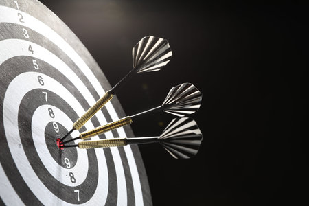 Targeting. Dart board with arrows on dark background, closeup