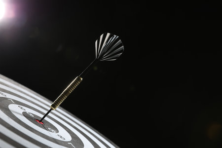 Targeting. Dart board with arrow on dark background, closeup. Space for textの写真素材