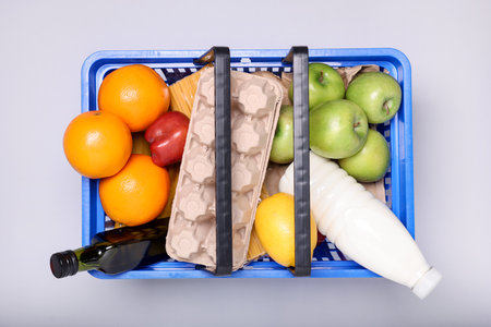 Plastic shopping basket full of products on light background, top viewの写真素材