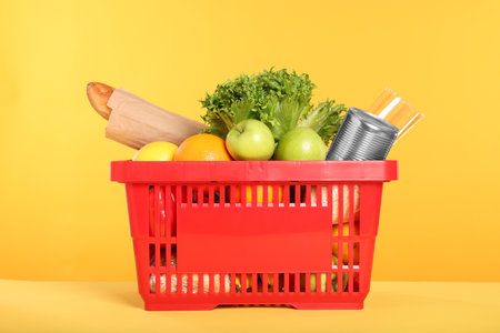 Shopping basket with different food products on yellow backgroundの写真素材