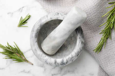 Mortar with rosemary, pestle and cloth on white marble table, flat layの写真素材