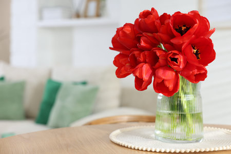 Beautiful red tulips in vase on wooden table indoors, space for textの写真素材
