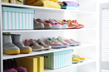 Different footwear and clothes on shelves indoors, closeup. Shoe storageの写真素材