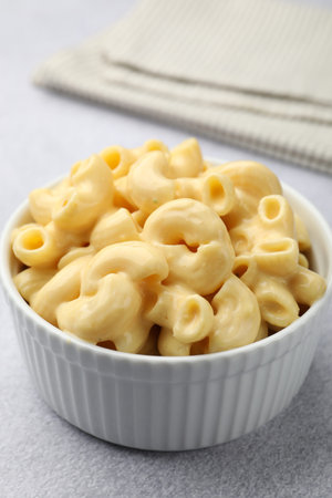 Delicious pasta with cheese sauce and fork on grey table, closeup