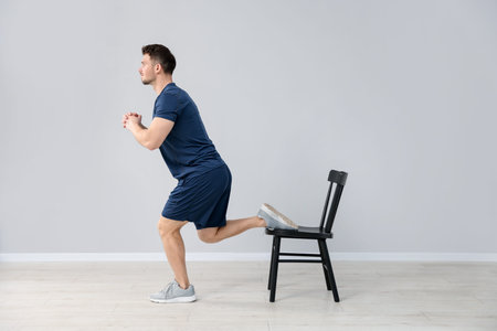 Handsome man exercising with chair at home