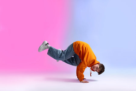 Boy in stylish clothes dancing on color background