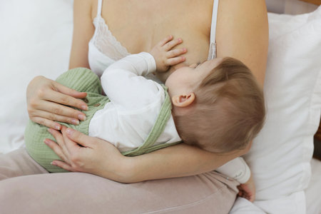 Mother breastfeeding her little baby on bed at home, closeupの写真素材